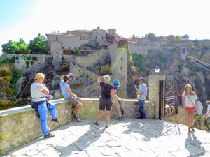 people looking at an ancient building in Meteora
