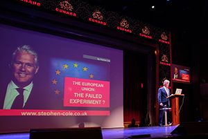 a lecturer on a stage on the Cunard QM2