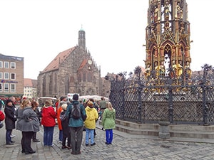 people on a plaza by an ornate tower
