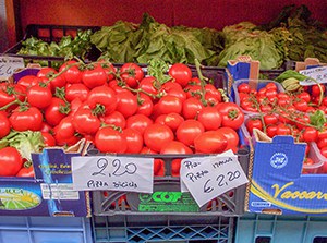 tomatoes in a marketan artist paiting a harbor scene in Cinque Terre Italy