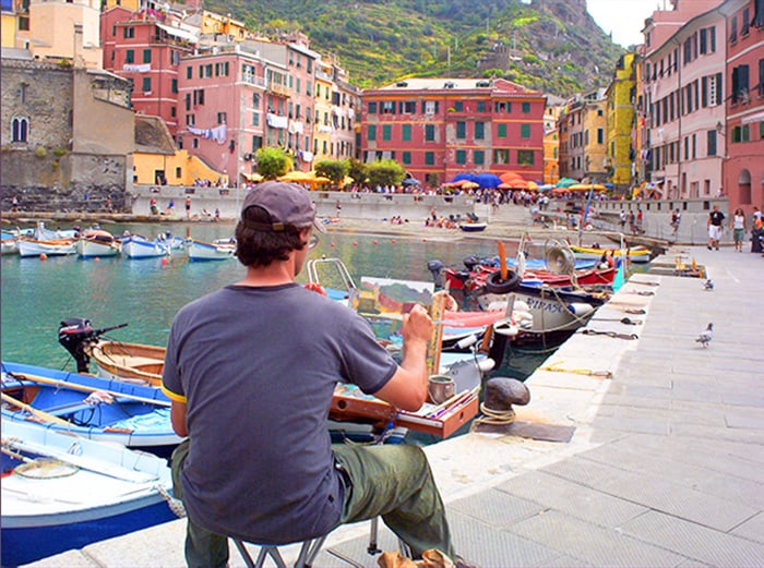 an artist paiting a harbor scene in Cinque Terre Italy