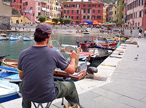 an artist paiting a harbor scene in Cinque Terre Italy