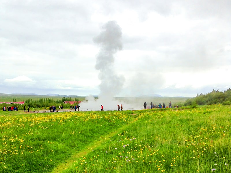 people by a geyser on an Iceland tour