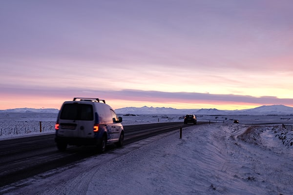 cars on road at sunrise driving to the Iceland ice caves