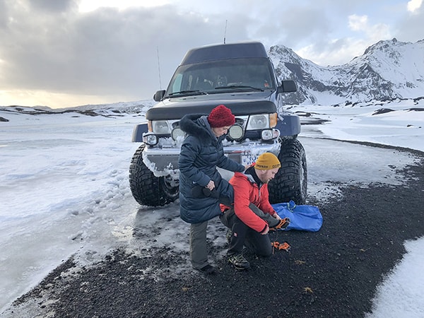 attaching crampons to boots before walking to the Iceland ice caves