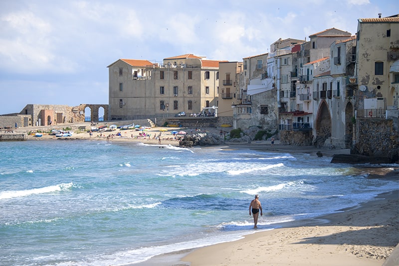 a man walking along a beach in Sicily