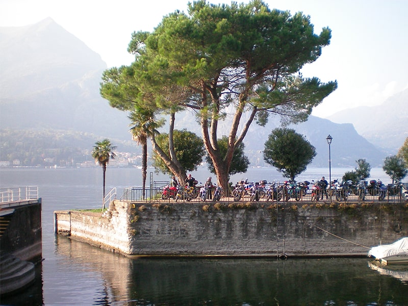 people sitting under a tree on the shore of Lake Como, one of the best places to visit in Italy
