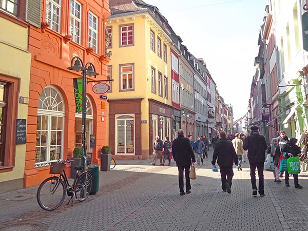 people waling past colorful old buildings