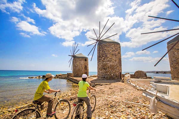 tourists on a Greece holiday looking at an old windmill