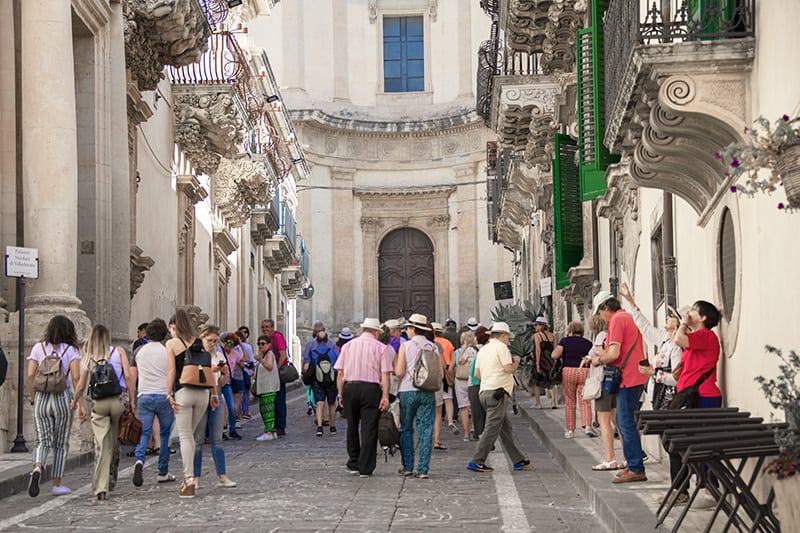 a tour group on a street - cities in Sicily