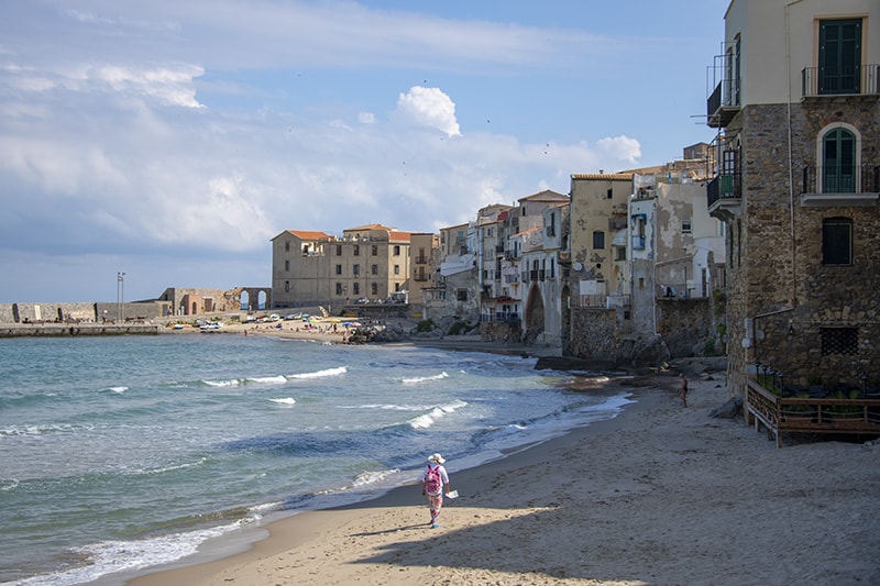 an man walking along a beach - airports in sicily