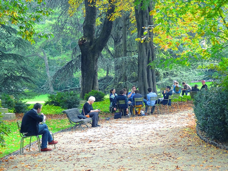 people sitting on a park path visited on a walking tour of Paris