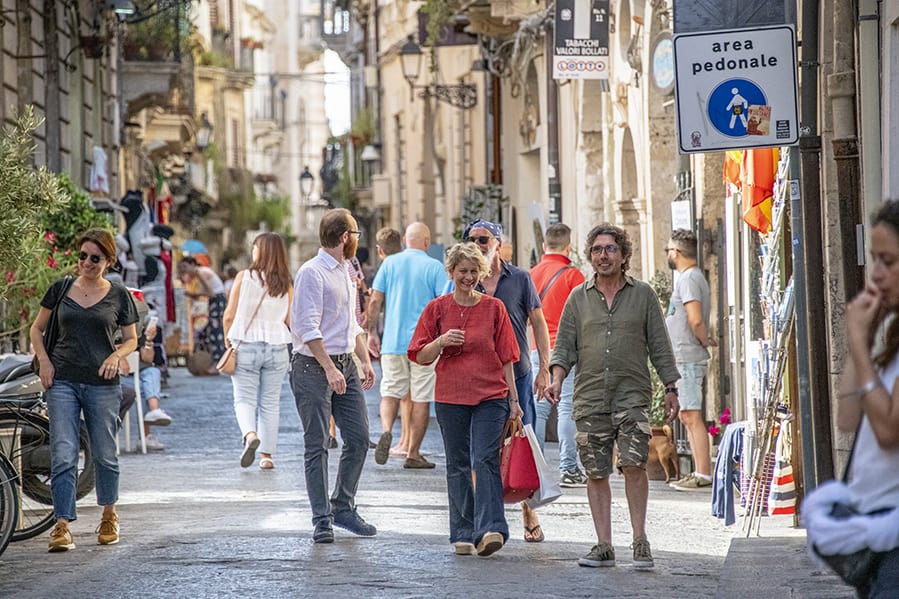 people on a street seen while touring Sicily by car