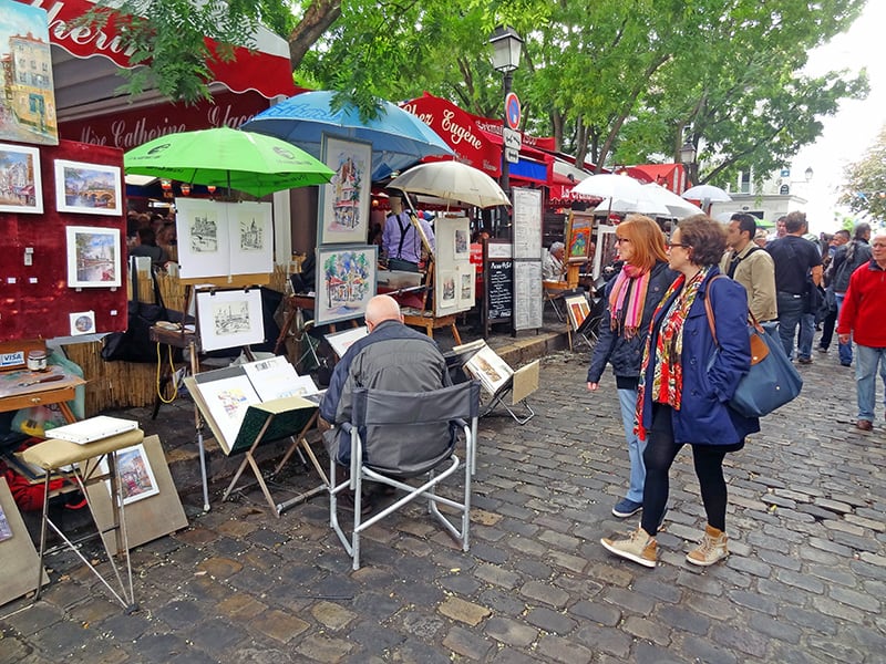 women looking at sidewalk artists on a Paris itineray