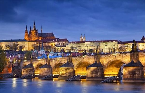 an ancient bridge lit up at night - best hotels in Prague