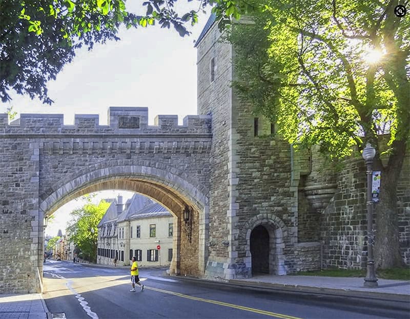 a man walking near a huge old city gate seen on a tour of Quebec City