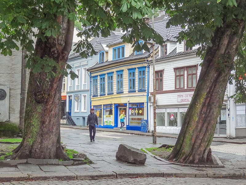 man on a street with colorful buildings - things to do in Bergen Norway