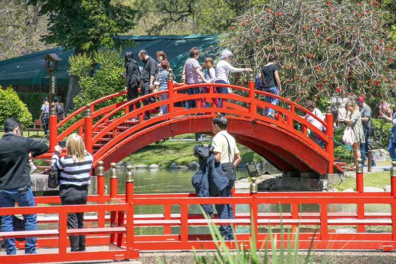 people on a red bridge in a garden in palermo, buenos aires