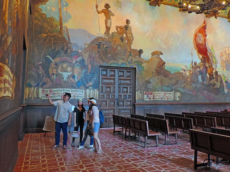 people looking at colorful murals in a courtroom