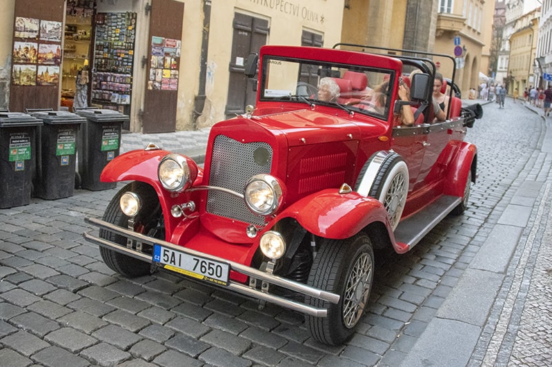 people getting around Prague in a red touring car