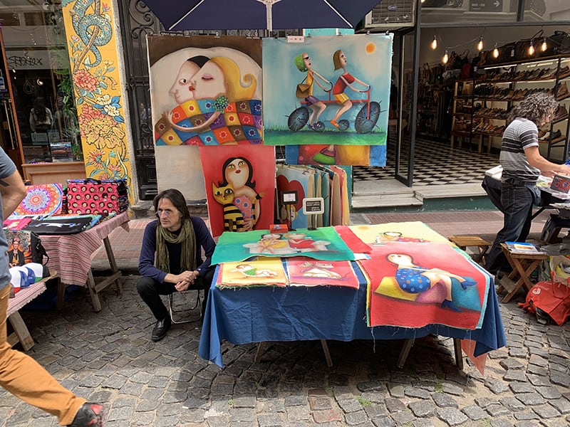 an artist sitting at a table in a street fair