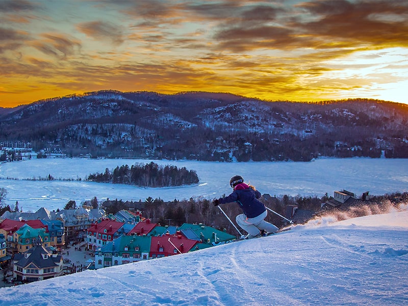 a skier at sunset skiing mount tremblant above mont tremblant village