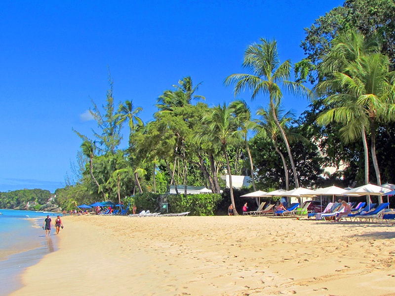 Travelers on a Barbados holiday walking on the beach