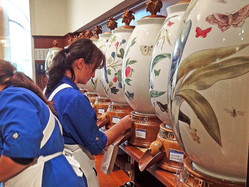 a woman grinfing coffee beans in Dallmayr, one of the shops to see during two days in Munich