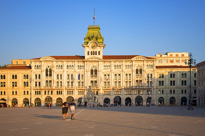 people walking across a large plaza with Venetian-style buildings