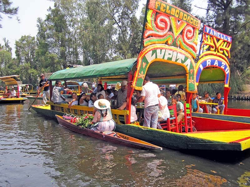 people on colorful boats in Xochimilco, on of the fun things to do in Mexico City