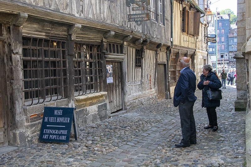 people looking at an old buillding seen on a trip to Normandy from Paris