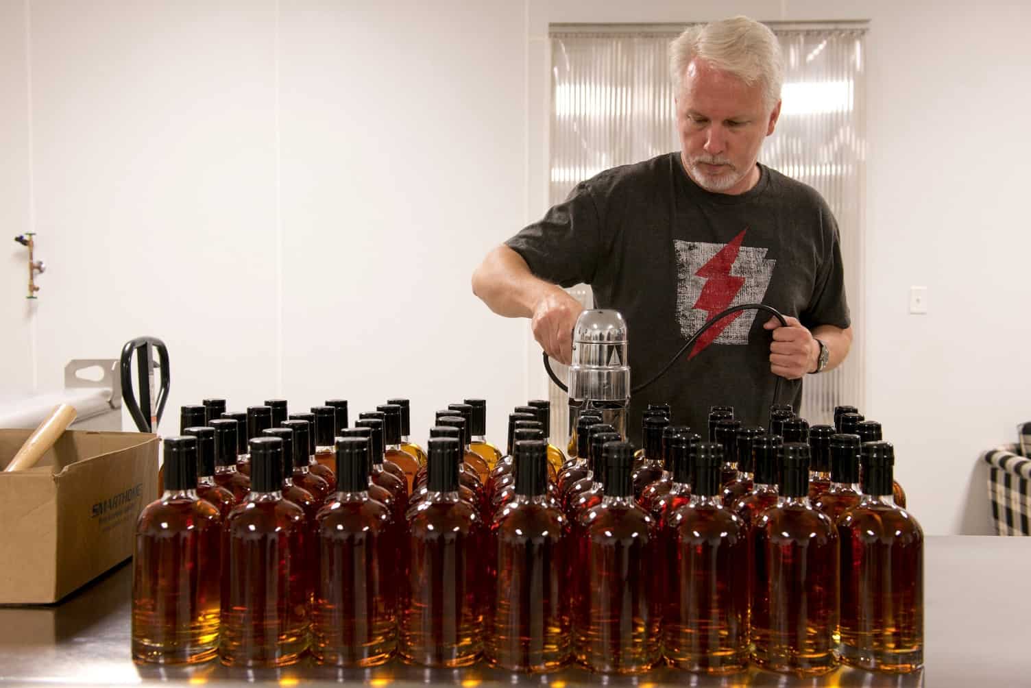 man filling liquor bottles in a distillery