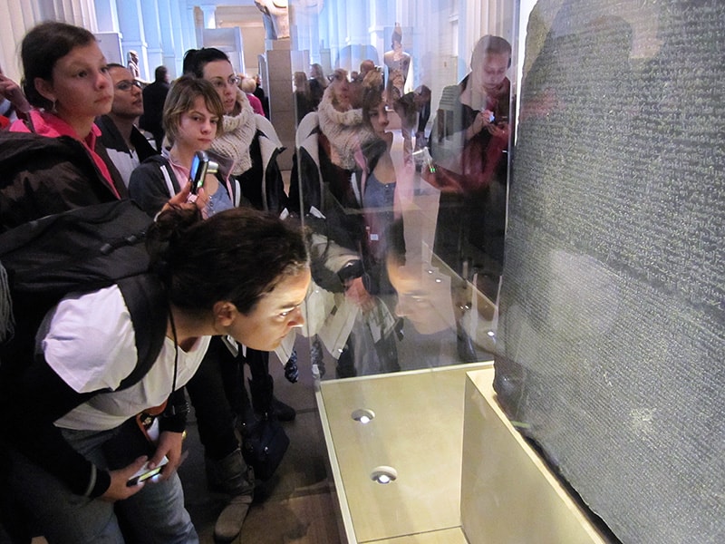 people on a London walking tour looking at the Rosetta Stone in te British Museum