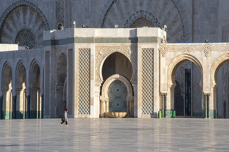 woman walking around a large mosque in Casablanca, one of the things to do in Morocco