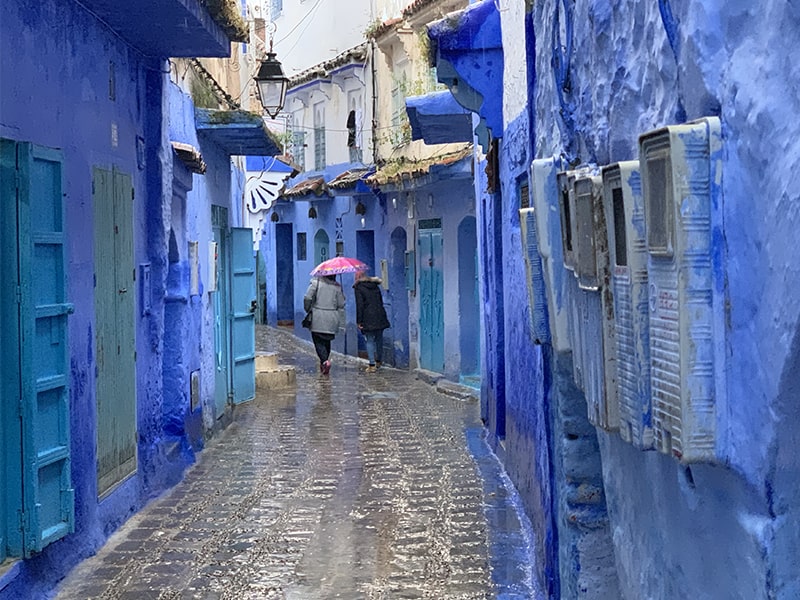 people walking past blue buildings in Chefchaouen, one of the things to do in Morocca