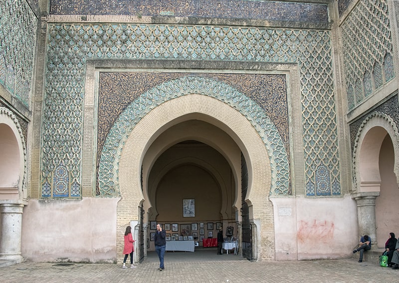 people walking by an immense doorway in Meknes, one of the places to visit in Morocco