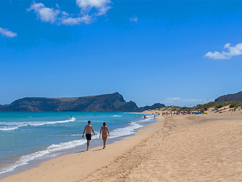 people walking along a beach in Madiera, a good place to recharge your batteries