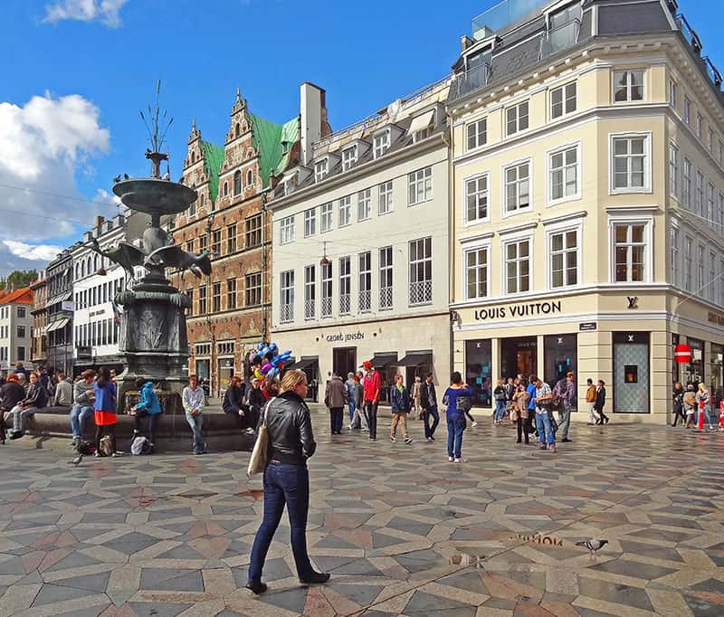 people on a wide shopping street near a fountain