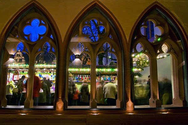 a view of a German Christmas market through gothic windws