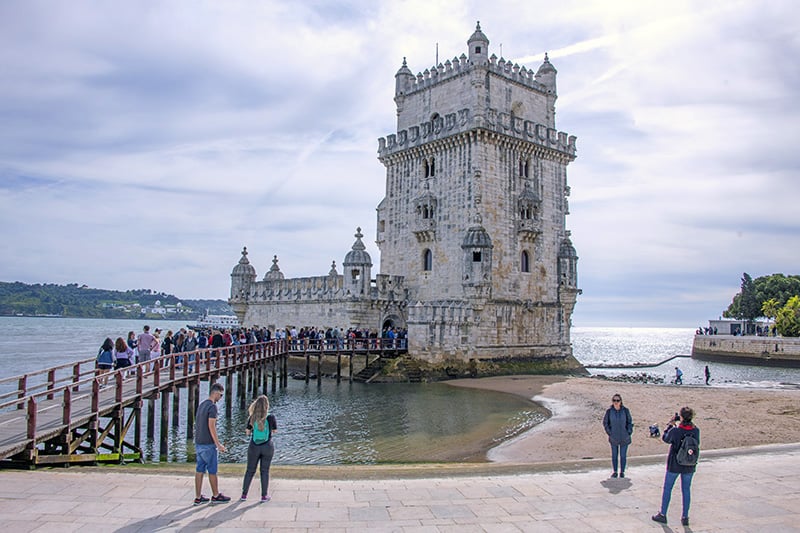 people looking at an old tower, one of the things to do in Lisbon