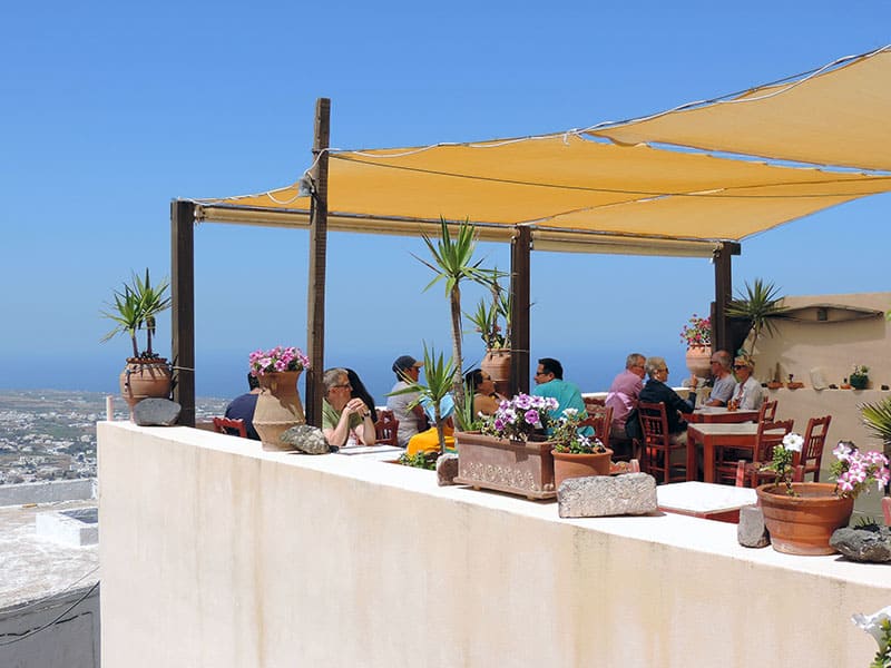 people dining in a cafe high above the island - what to do in Santorini