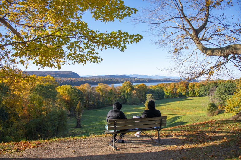 couple on a bench looking at the woods and river in the Hudson Valley
