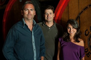 3 people standing by large wine barrels