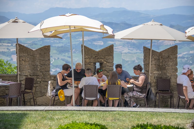 people having lunch under umbrellas by stone columns