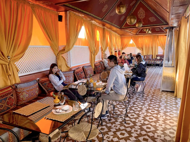people having breakfast in a room with orange curtains