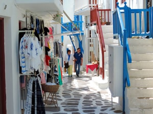 a couple walking past Boutiques in old town Mykonos 