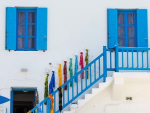 blue shutters and stairs with colorful scarves on a wall in old town Mykonos 