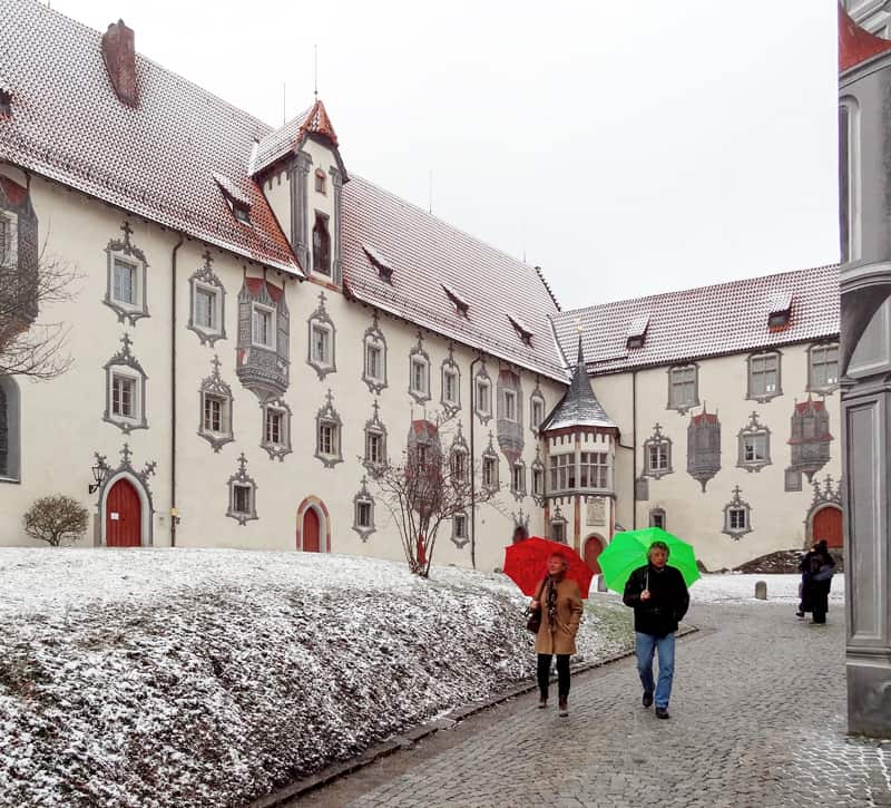 people with red and grenn umbrellas outside a building in Fussen