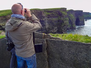 man looking at tall cliffs