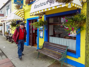 a man walking past a yellow building on Ireland's West Coast